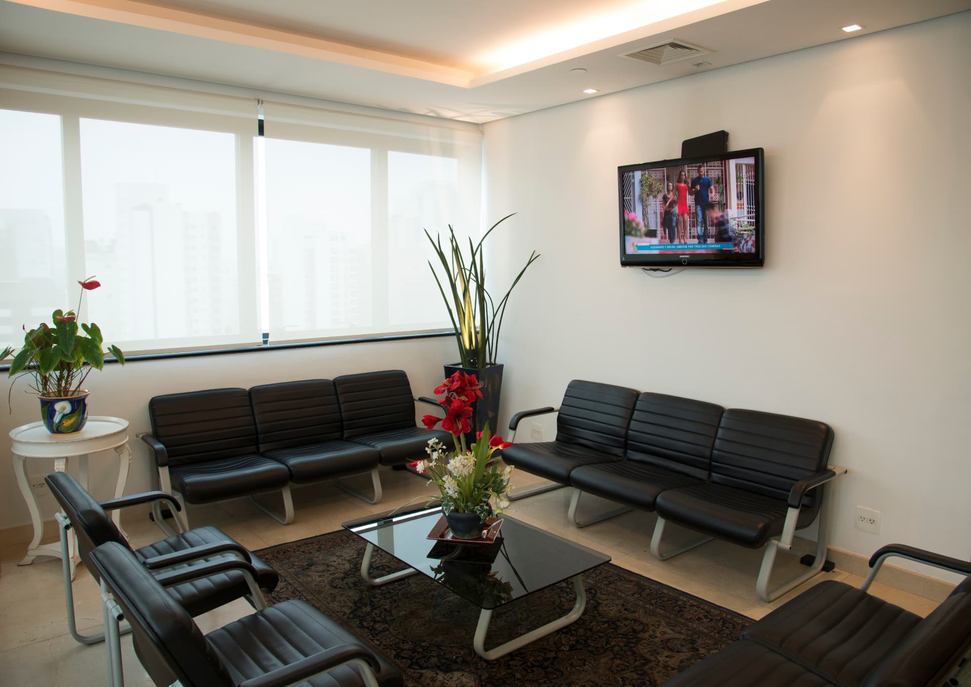 Sala de espera principal ampla com poltronas e televisão